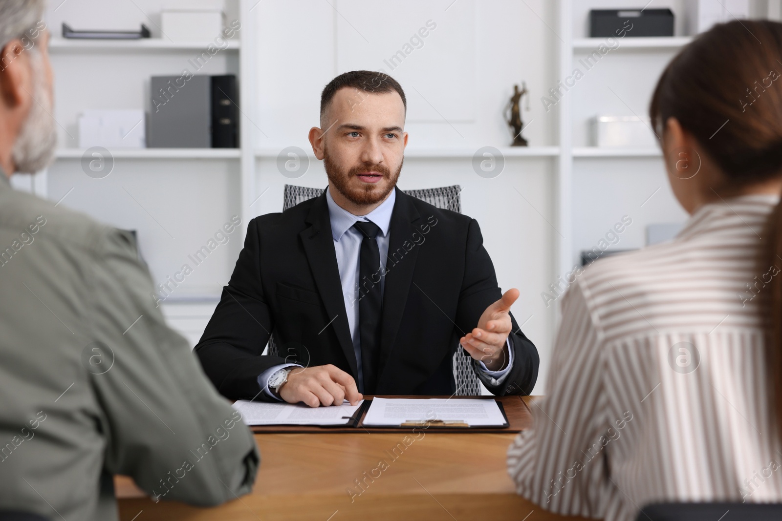 Photo of Man and woman having meeting with professional notary at wooden desk indoors