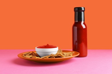 Photo of Tasty ketchup and pieces of dry bread on color background