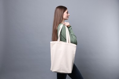 Photo of Woman with blank shopper bag on grey background. Mockup for design