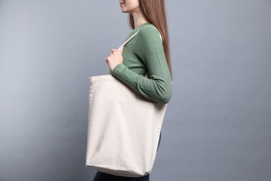 Photo of Woman with blank shopper bag on grey background, closeup. Mockup for design