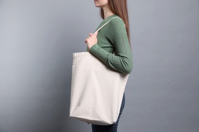 Photo of Woman with blank shopper bag on grey background, closeup. Mockup for design