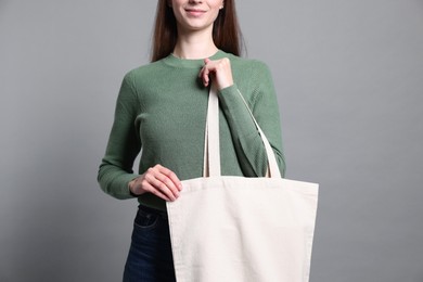 Photo of Woman with blank shopper bag on grey background, closeup. Mockup for design