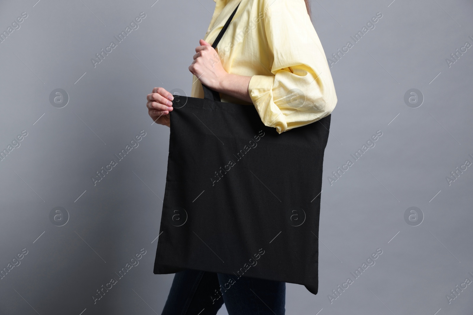 Photo of Woman with blank shopper bag on grey background, closeup. Mockup for design