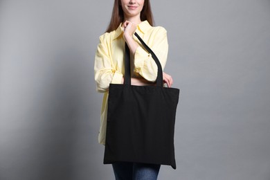 Photo of Woman with blank shopper bag on grey background, closeup. Mockup for design