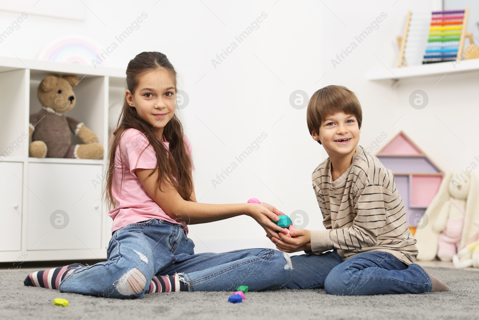 Photo of Children playing with balancing stones on floor indoors