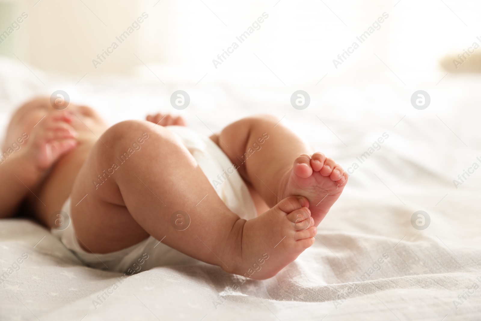 Photo of Cute little baby in diaper on bed indoors, selective focus