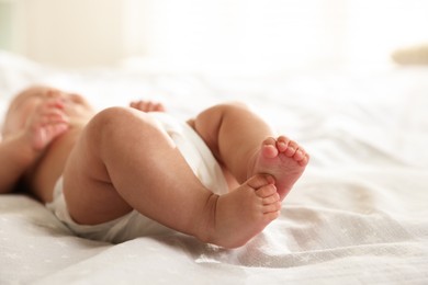 Photo of Cute little baby in diaper on bed indoors, selective focus