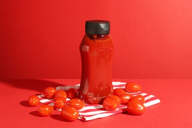 Photo of Bottle of ketchup and tomatoes on red background