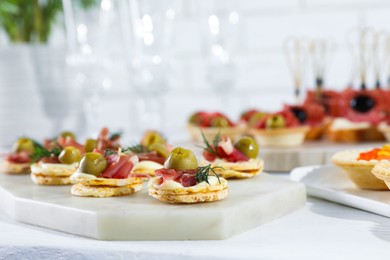 Photo of Many different tasty canapes on white wooden table, closeup