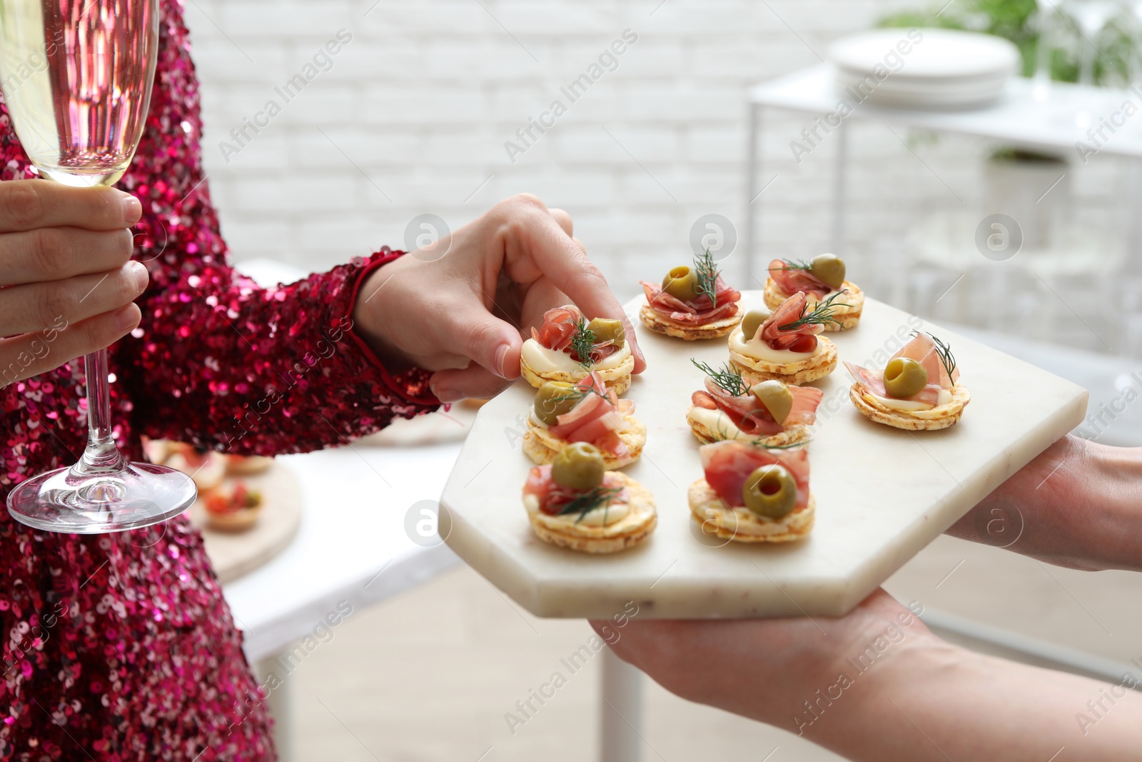 Photo of Woman taking tasty canape from waiter with board indoors, closeup