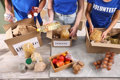 Photo of Volunteers packing food donations at tables indoors, closeup