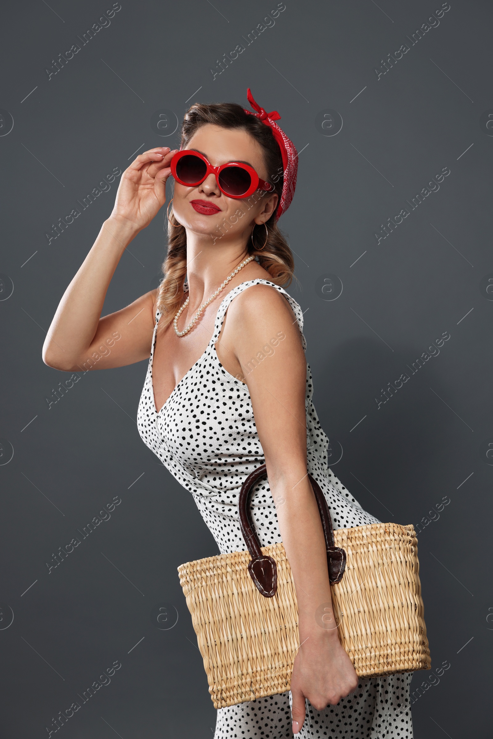 Photo of Beautiful pin-up woman with bag posing on grey background