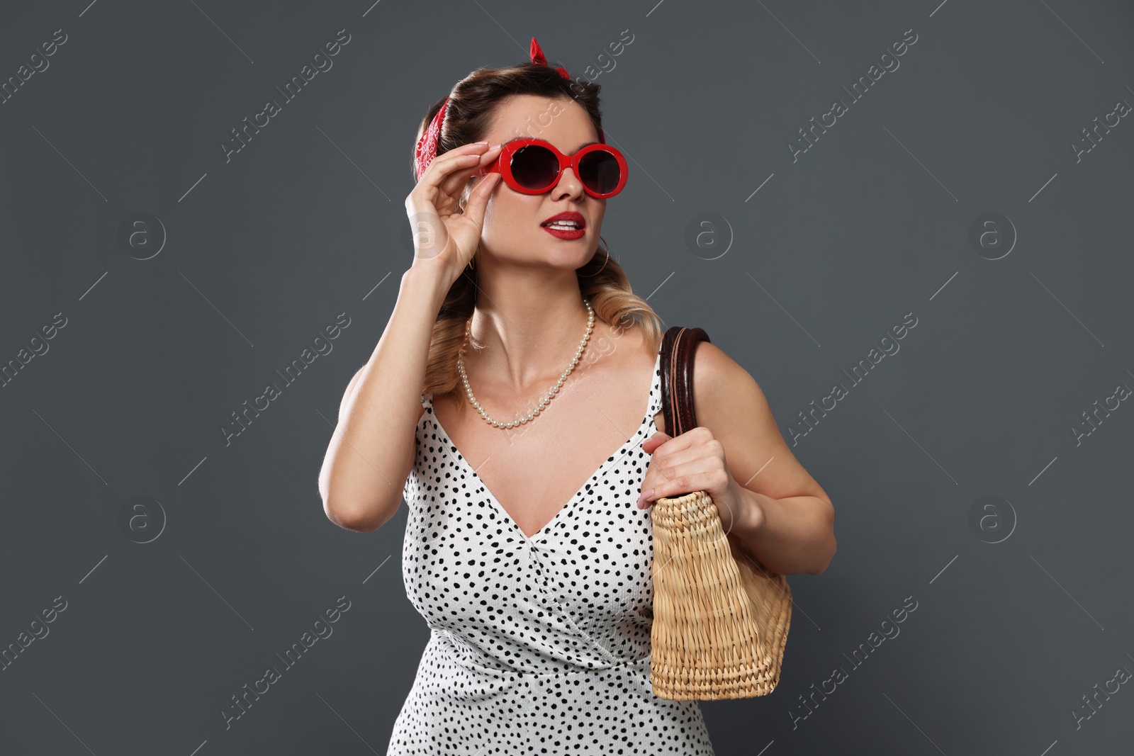 Photo of Beautiful pin-up woman with bag posing on grey background