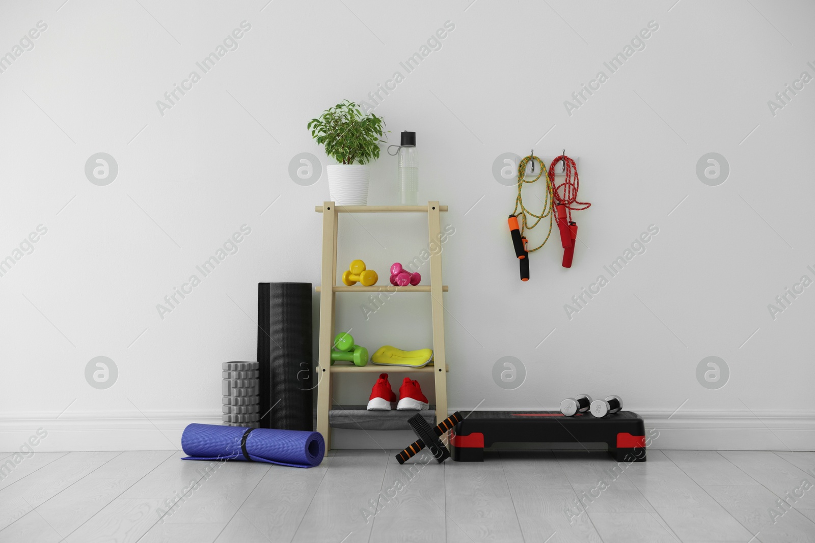 Photo of Different fitness equipment near white wall indoors