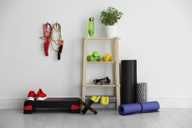 Different fitness equipment near white wall indoors