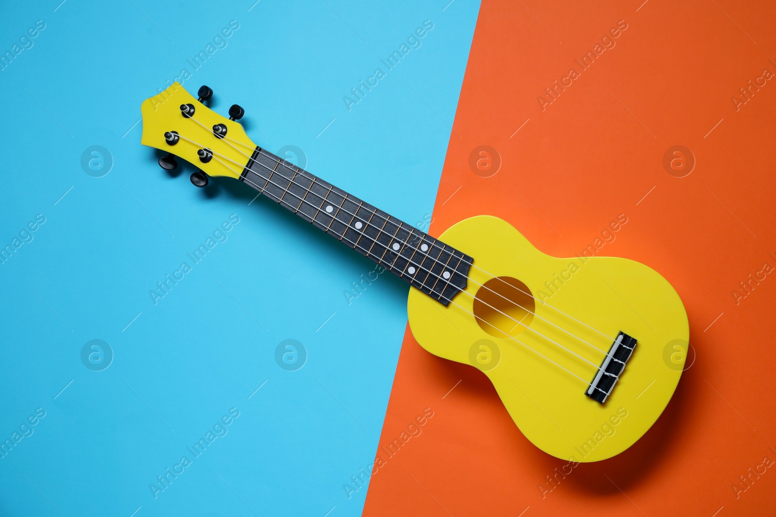 Photo of One ukulele on color background, top view