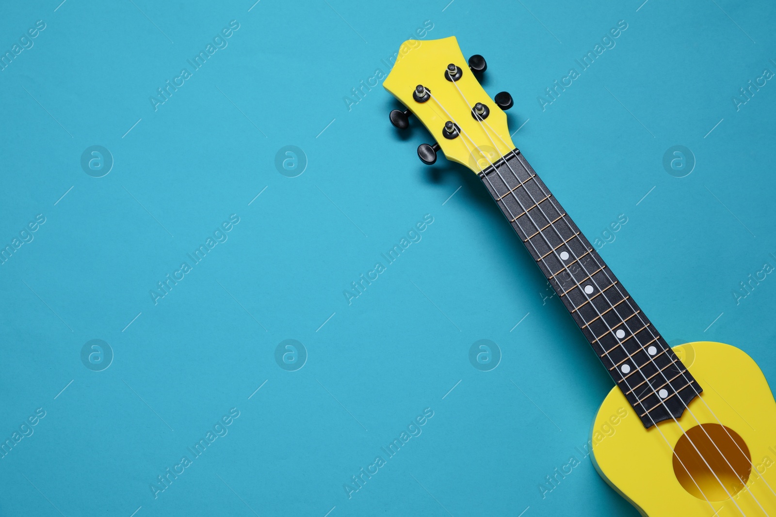 Photo of One ukulele on light blue background, top view. Space for text