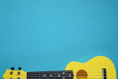 Photo of One ukulele on light blue background, top view. Space for text