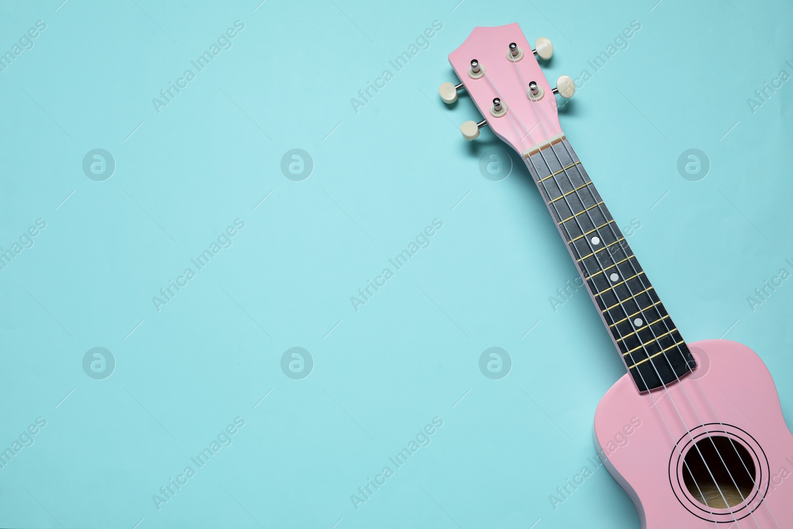 Photo of One ukulele on light blue background, top view. Space for text