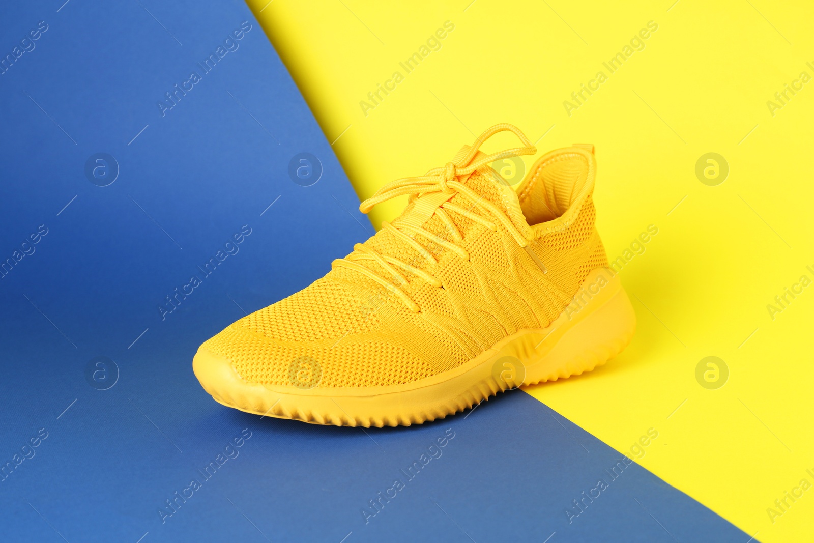 Photo of Stylish yellow sneaker on color background. Sports footwear