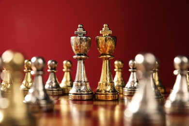 Photo of Golden and silver chess kings among pawns on chessboard. Competition concept