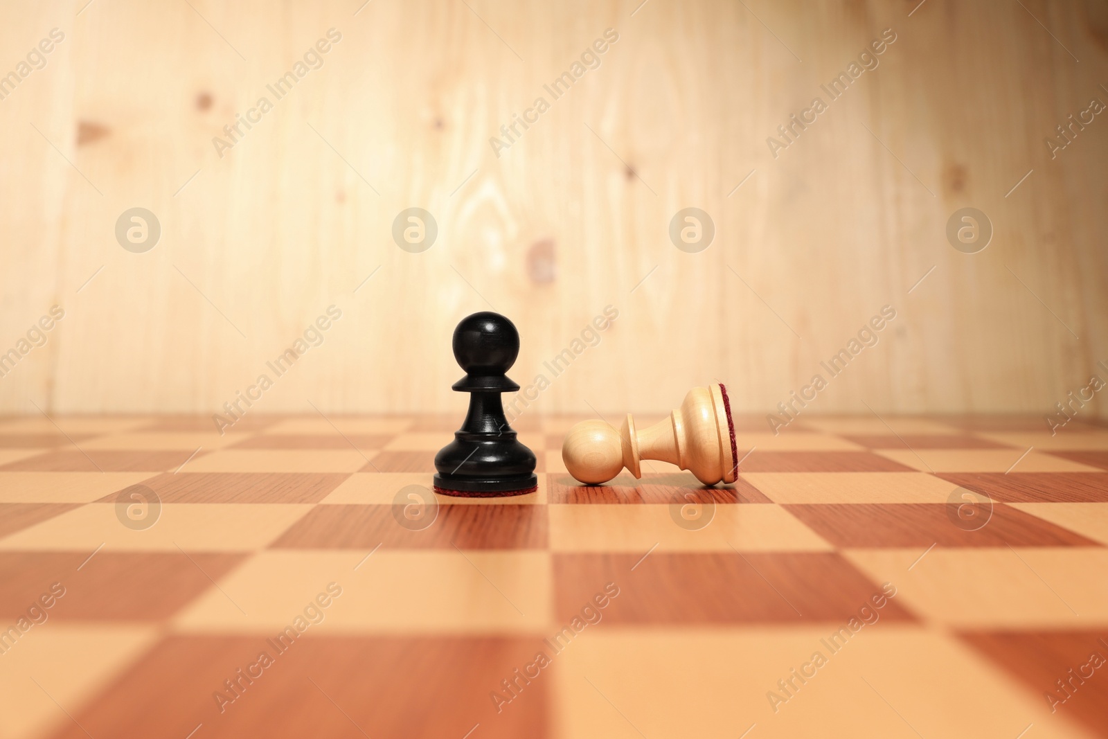 Photo of Black pawn near fallen white one in middle of chessboard. Competition concept