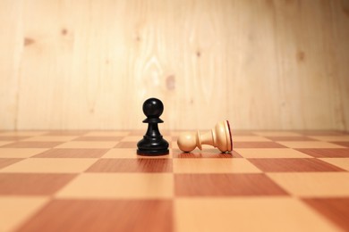 Photo of Black pawn near fallen white one in middle of chessboard. Competition concept