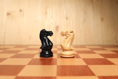 Photo of Black and white chess knights in middle of chessboard. Competition concept