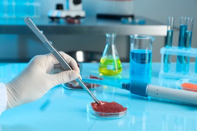 Photo of GMO concept. Scientist with piece of meat at table in laboratory, closeup