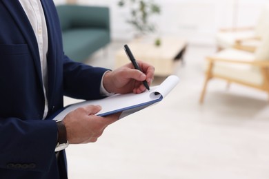 Photo of Real estate appraisal. Inspector with clipboard conducting property valuation at home, closeup. Space for text