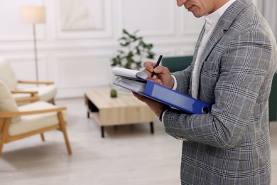 Photo of Real estate appraisal. Inspector with clipboard conducting property valuation at home, closeup. Space for text