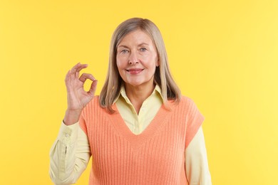 Photo of Senior woman showing okay gesture on yellow background