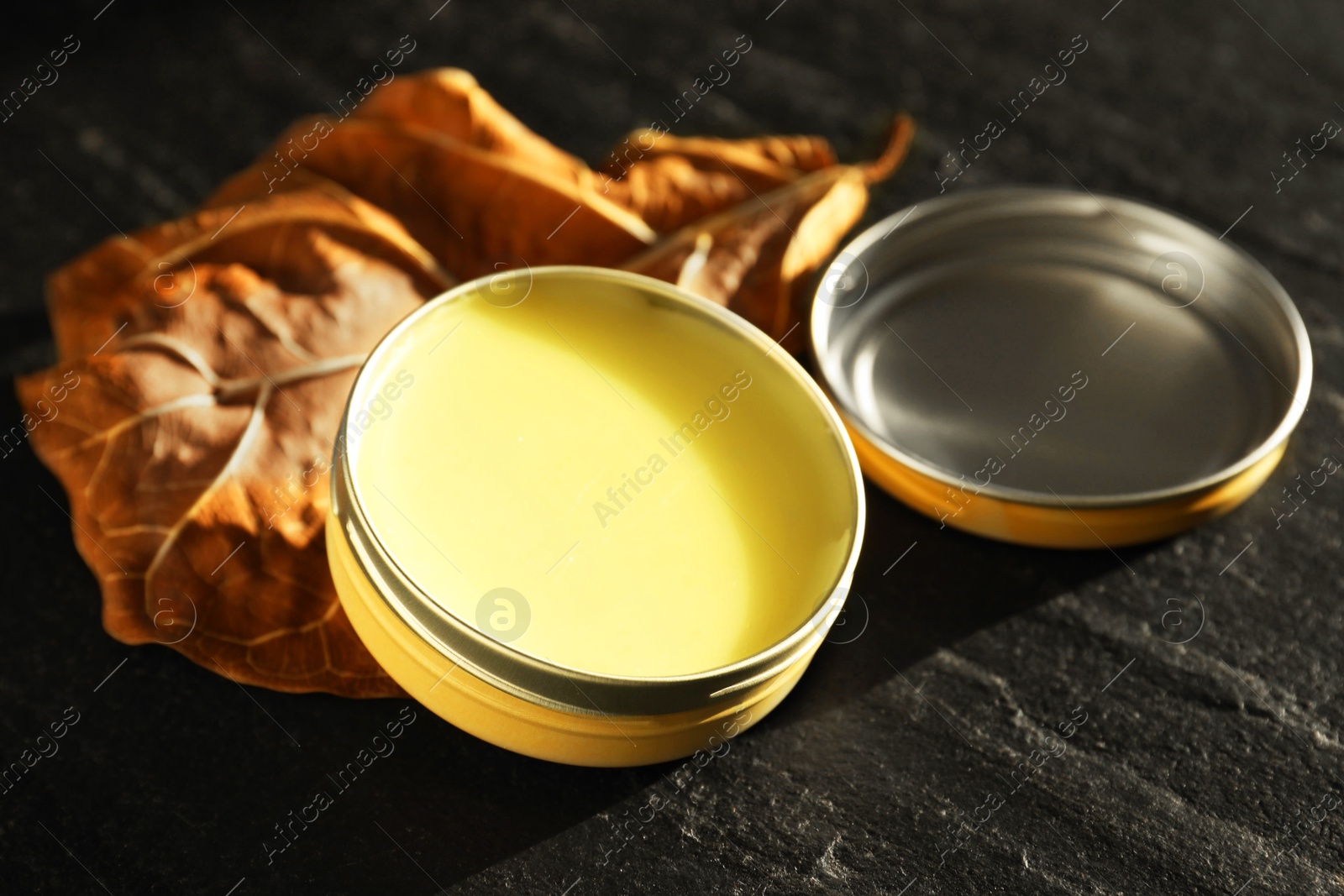 Photo of Natural solid perfume and dry leaf on black table, closeup