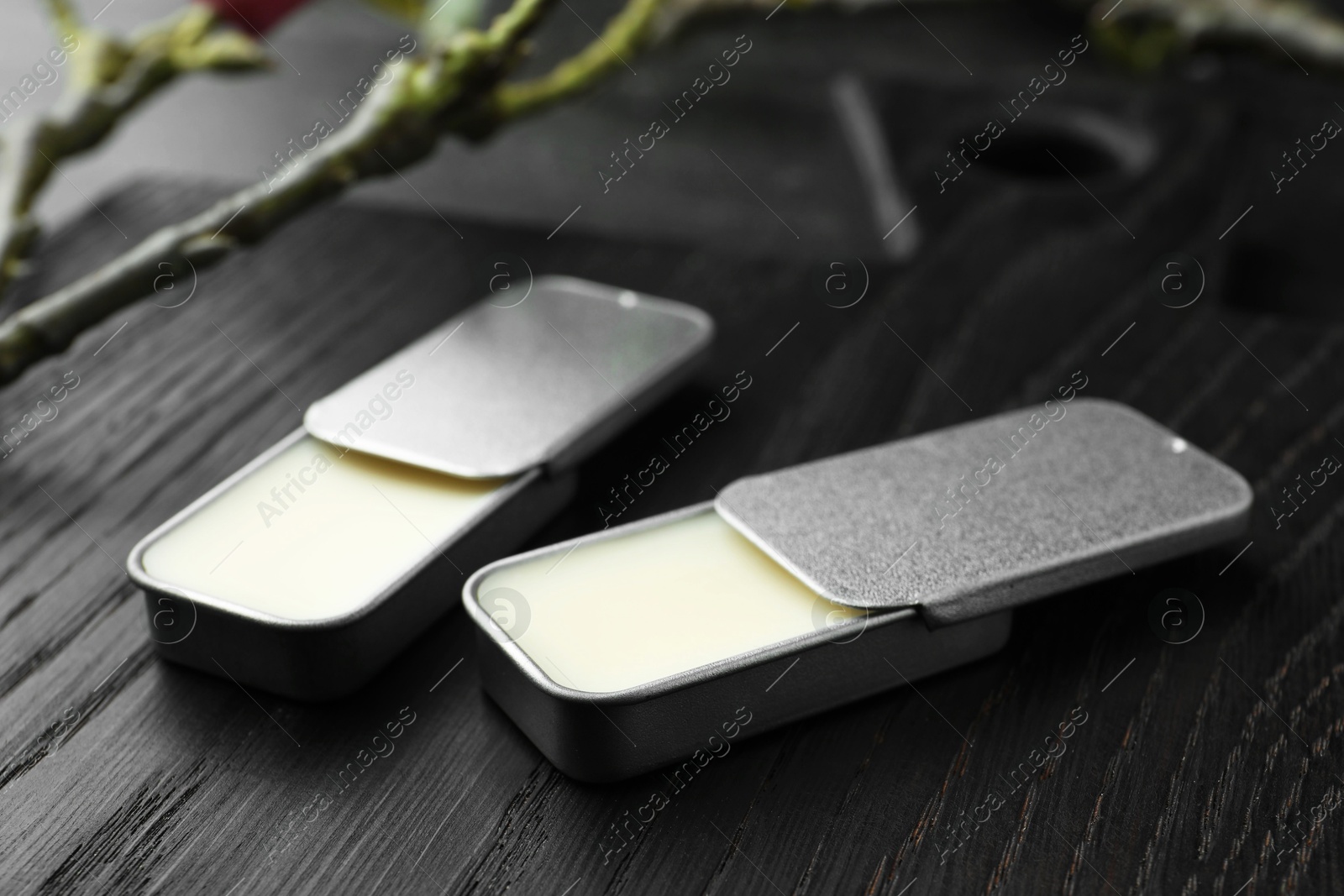 Photo of Natural solid perfume and branch on black wooden table, closeup