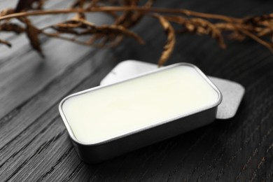 Photo of Natural solid perfume and dry branch on black wooden table, closeup