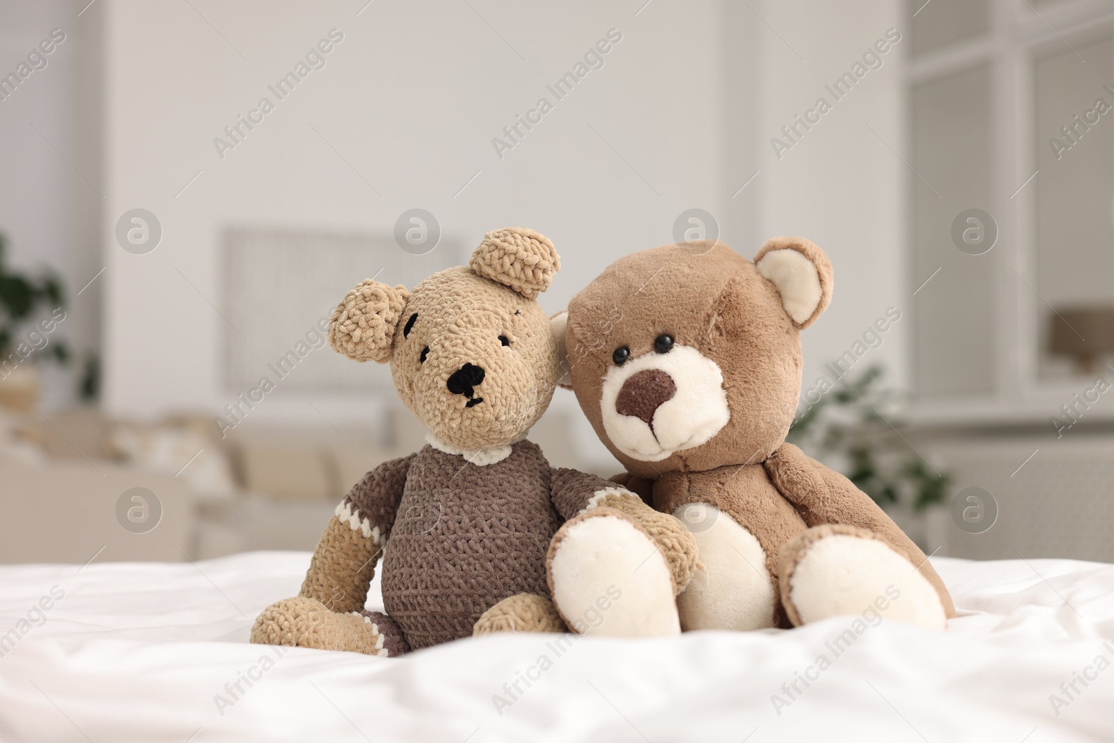 Photo of Cute toy bears on bed in room, closeup