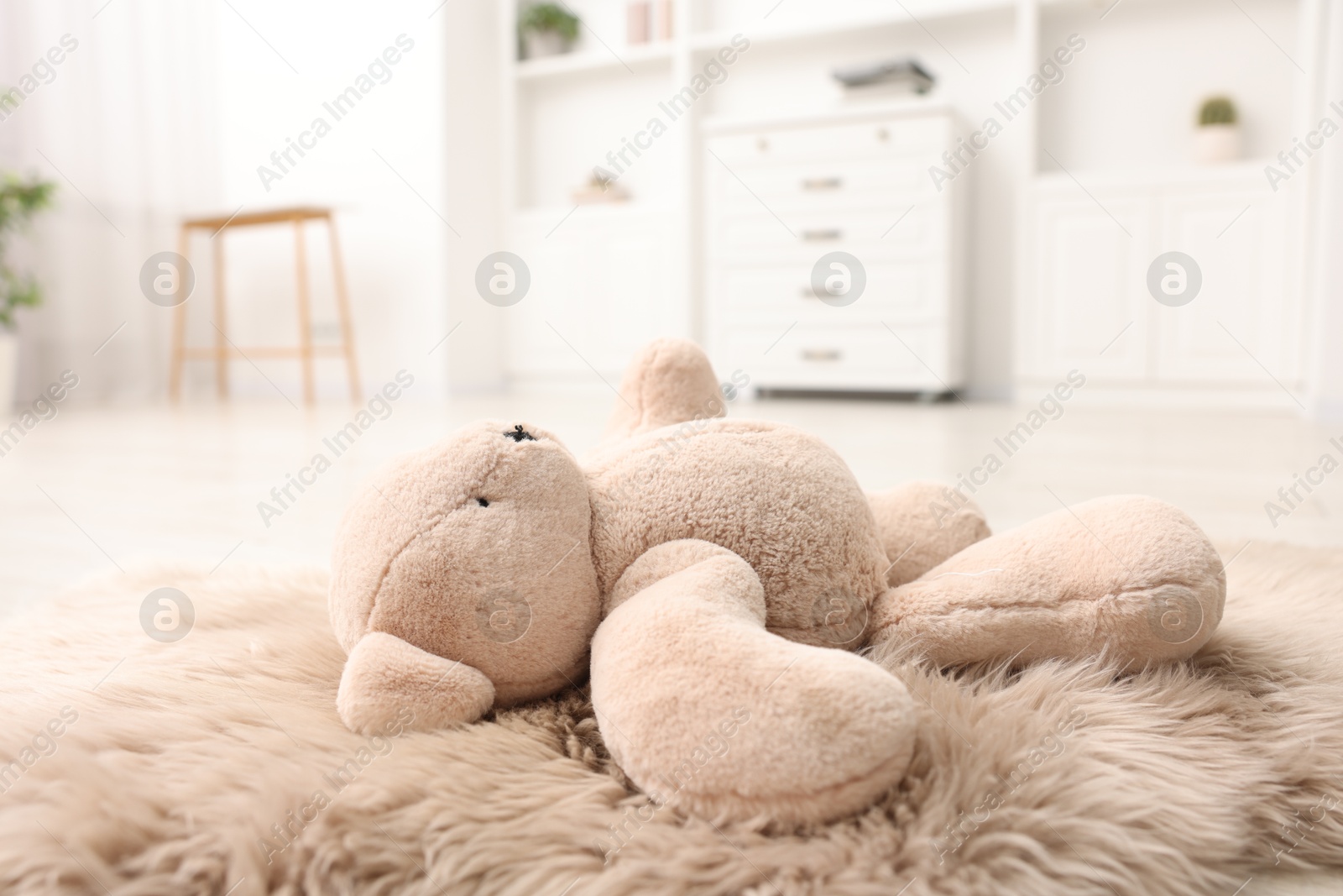 Photo of Lost teddy bear on fluffy rug in room, closeup