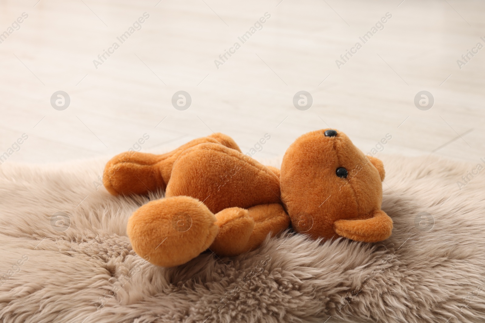 Photo of Lost teddy bear on fluffy rug indoors, closeup