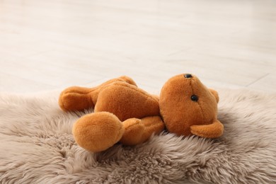 Photo of Lost teddy bear on fluffy rug indoors, closeup