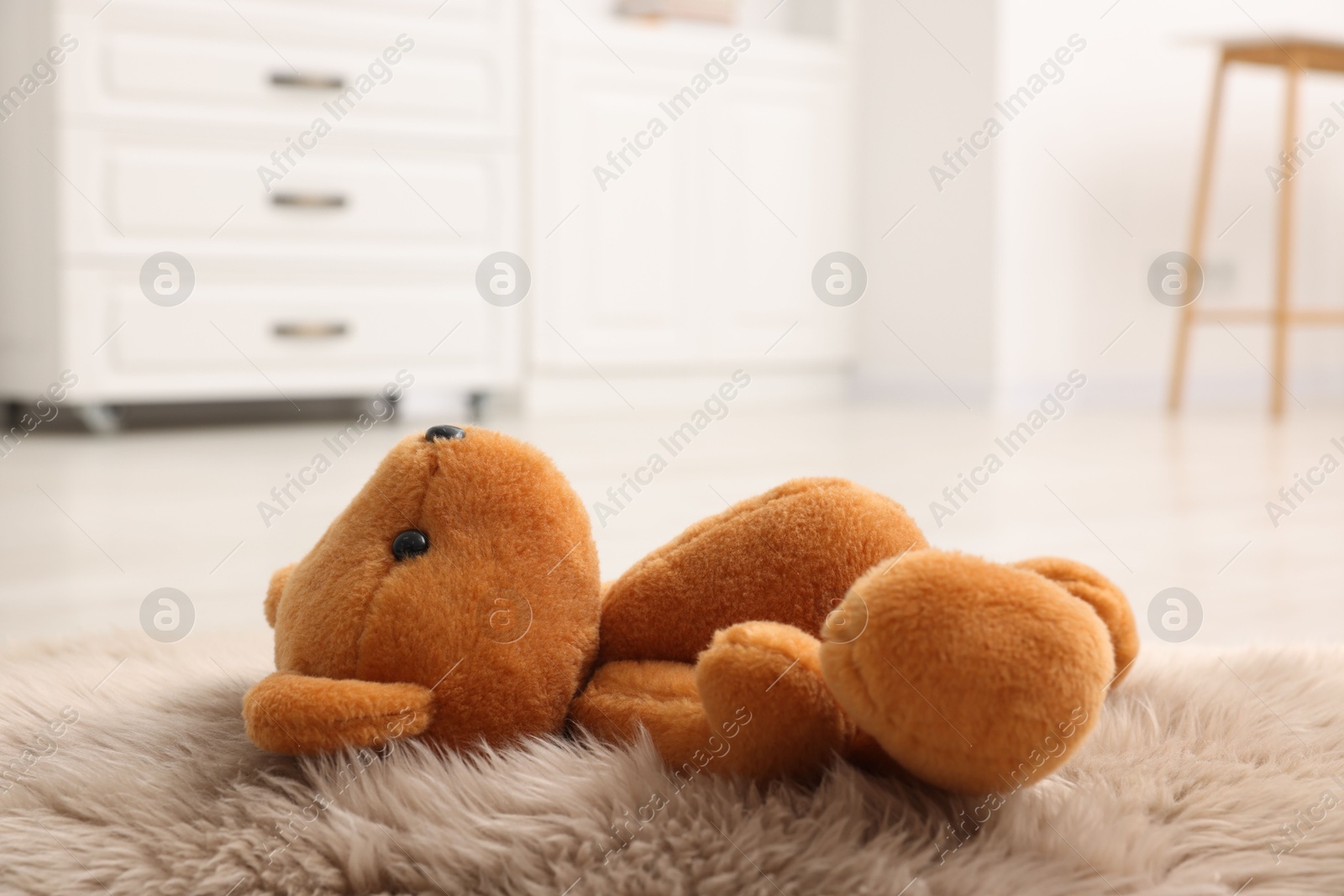 Photo of Lost teddy bear on fluffy rug in room, closeup