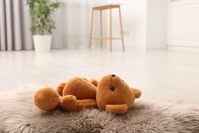 Photo of Lost teddy bear on fluffy rug in room, closeup