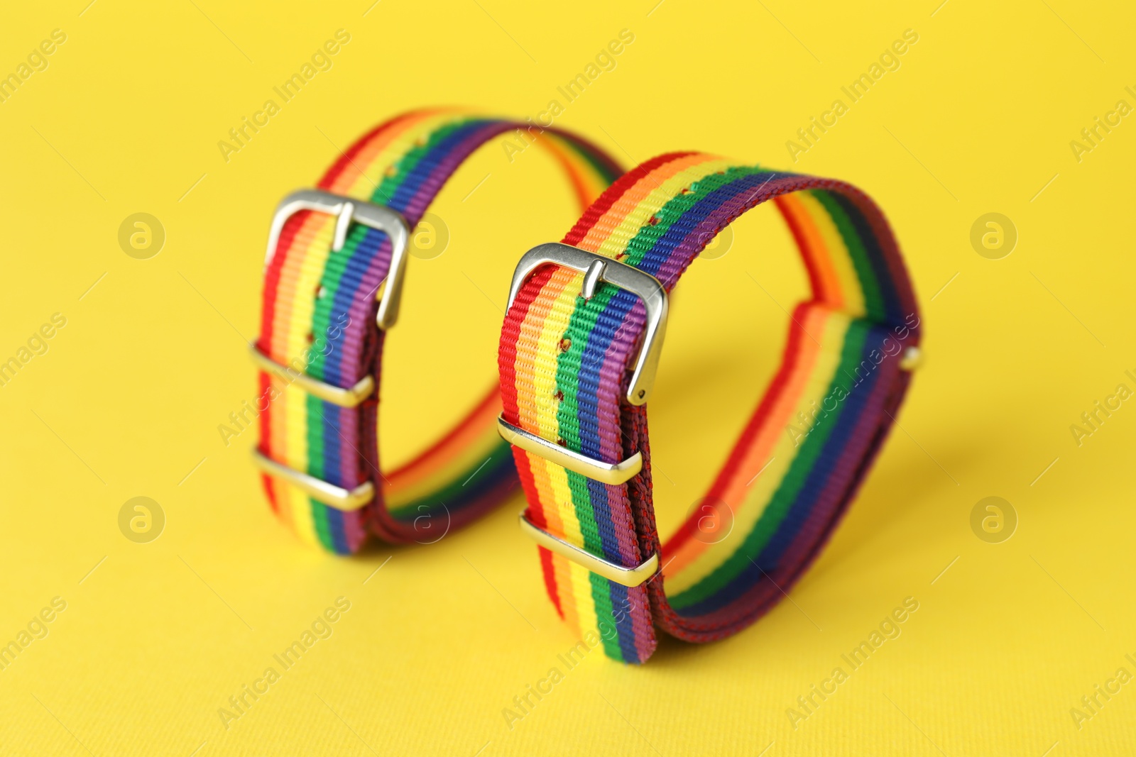 Photo of Two wristbands in LGBT colors on yellow background, closeup