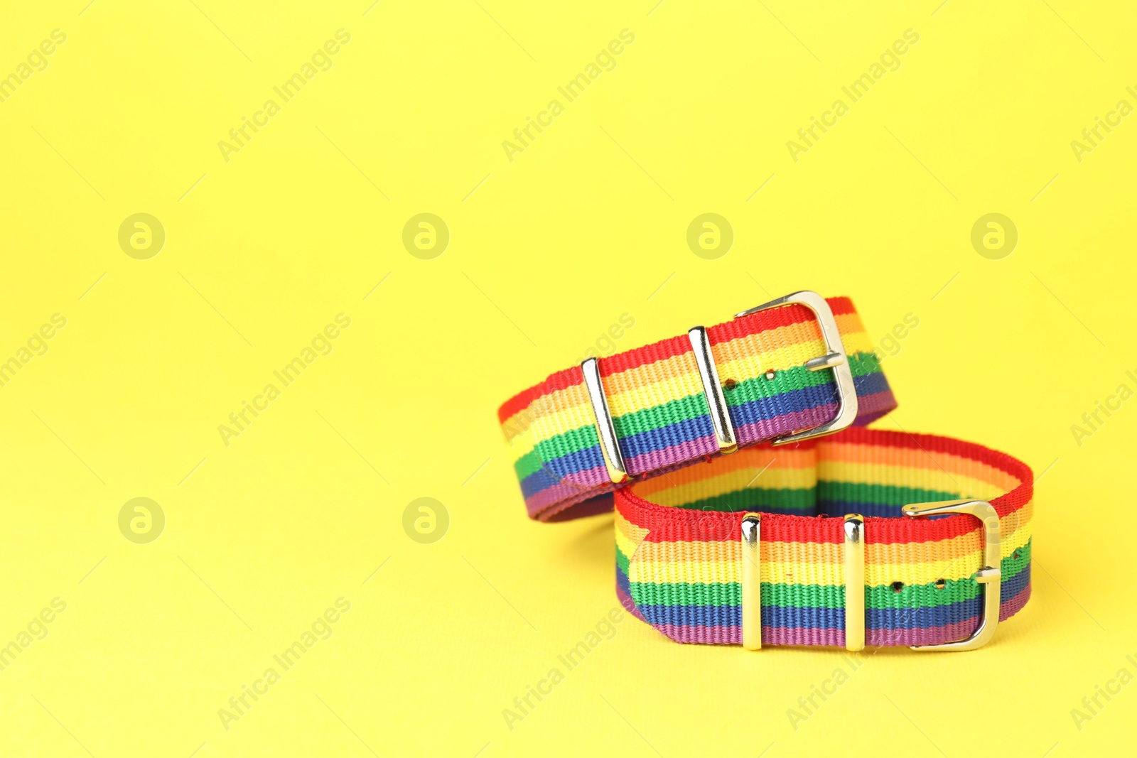 Photo of Two wristbands in LGBT colors on yellow background, space for text