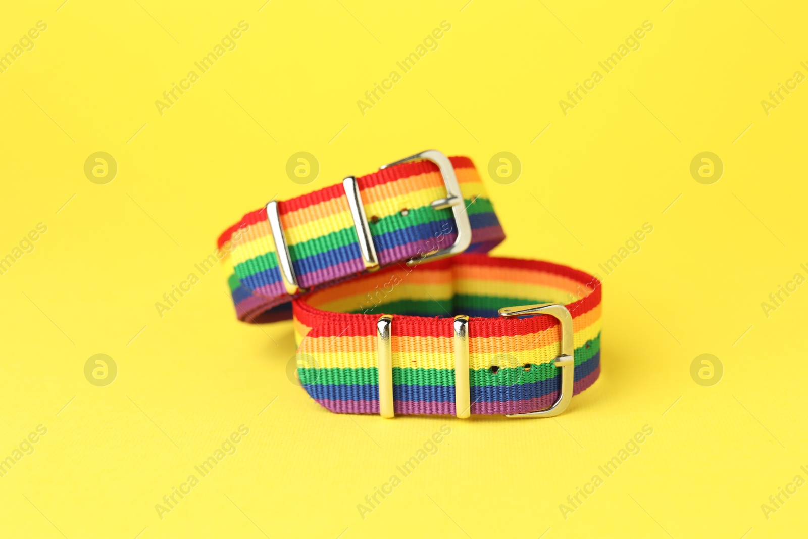 Photo of Two wristbands in LGBT colors on yellow background, closeup