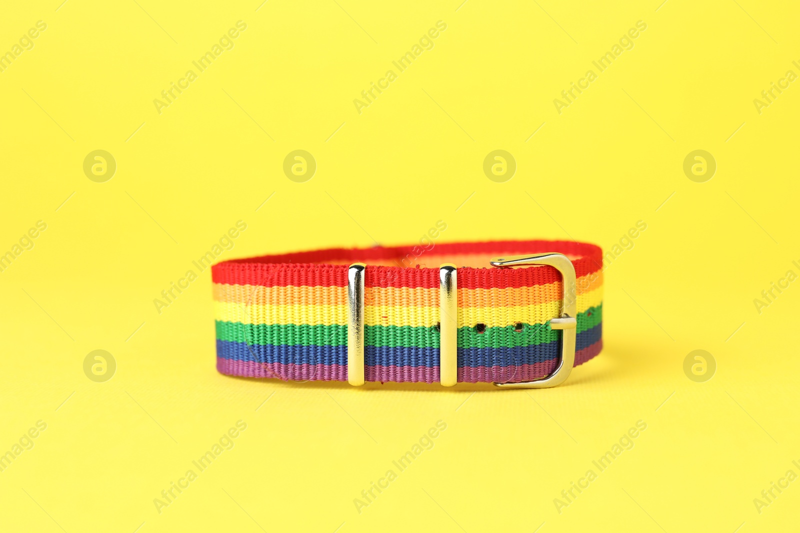 Photo of One wristband in LGBT colors on yellow background, closeup