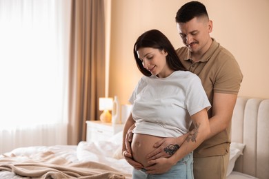 Pregnant woman and her husband at home, space for text