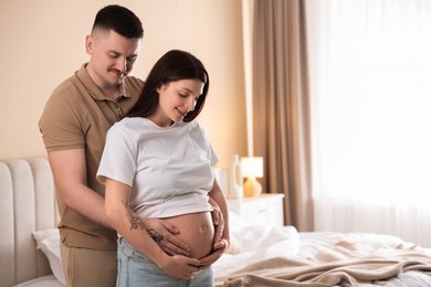 Photo of Pregnant woman and her husband at home, space for text