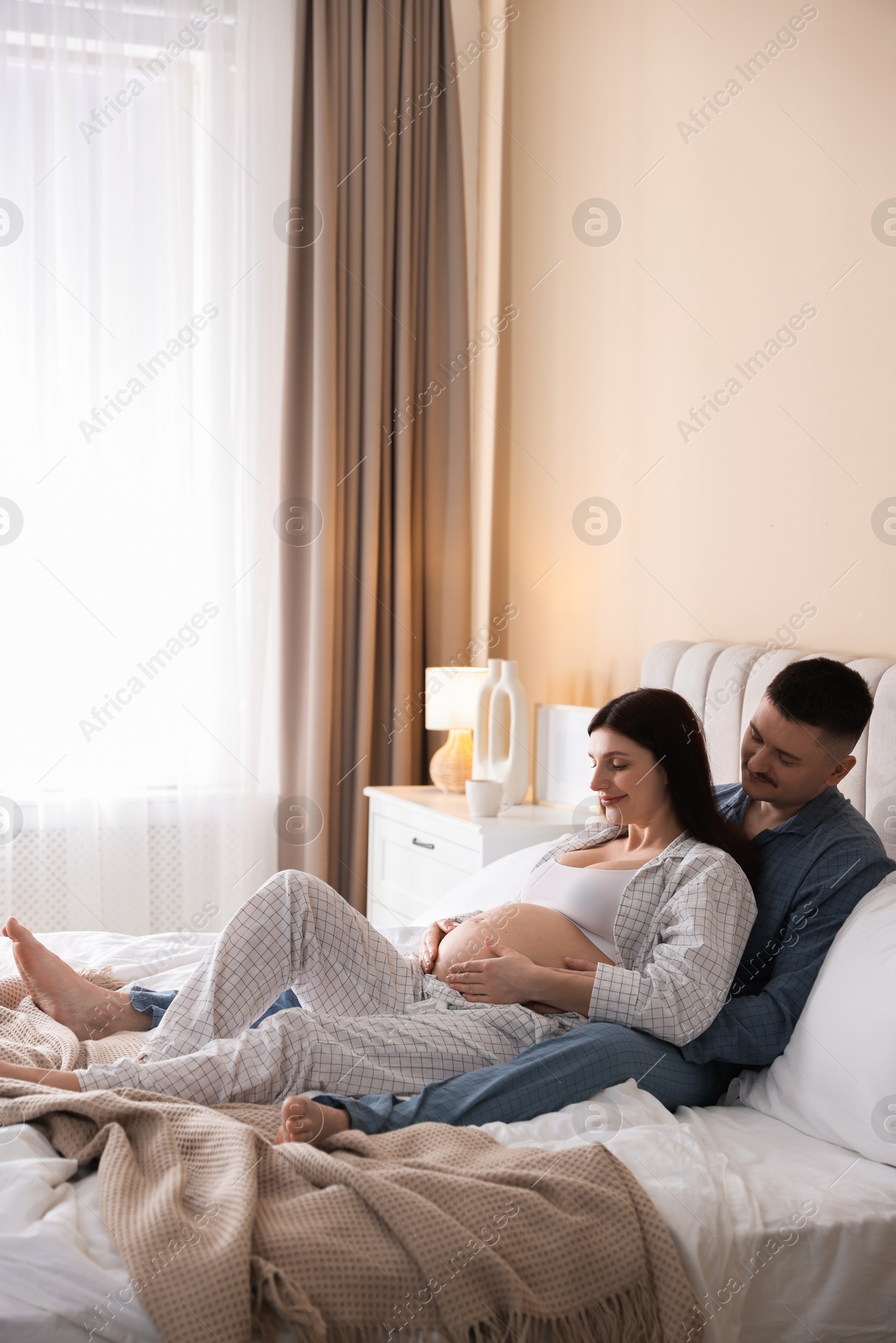 Photo of Pregnant woman and her husband on bed at home