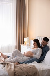 Photo of Pregnant woman and her husband on bed at home