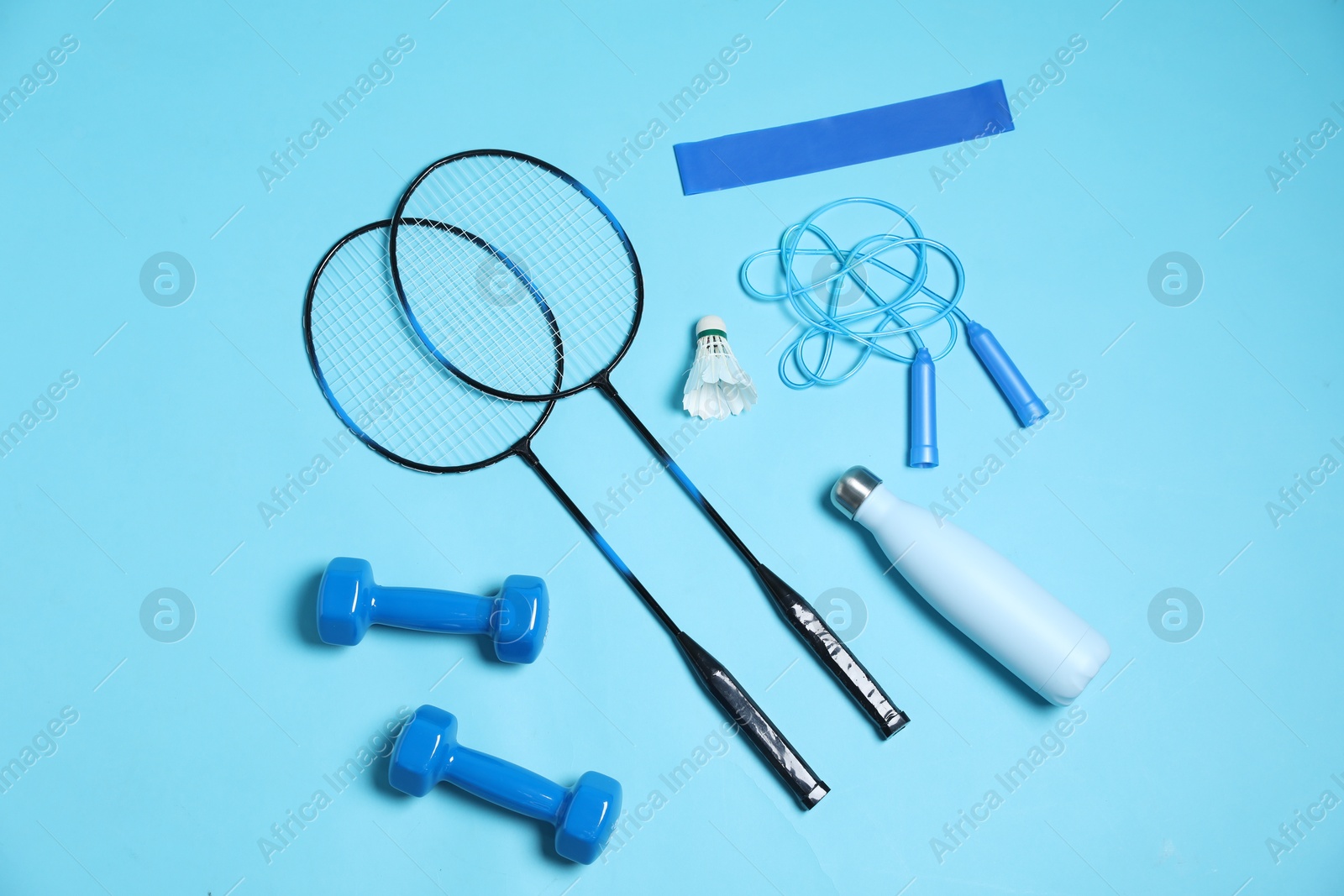 Photo of Different sports equipment and water bottle on light blue background, flat lay